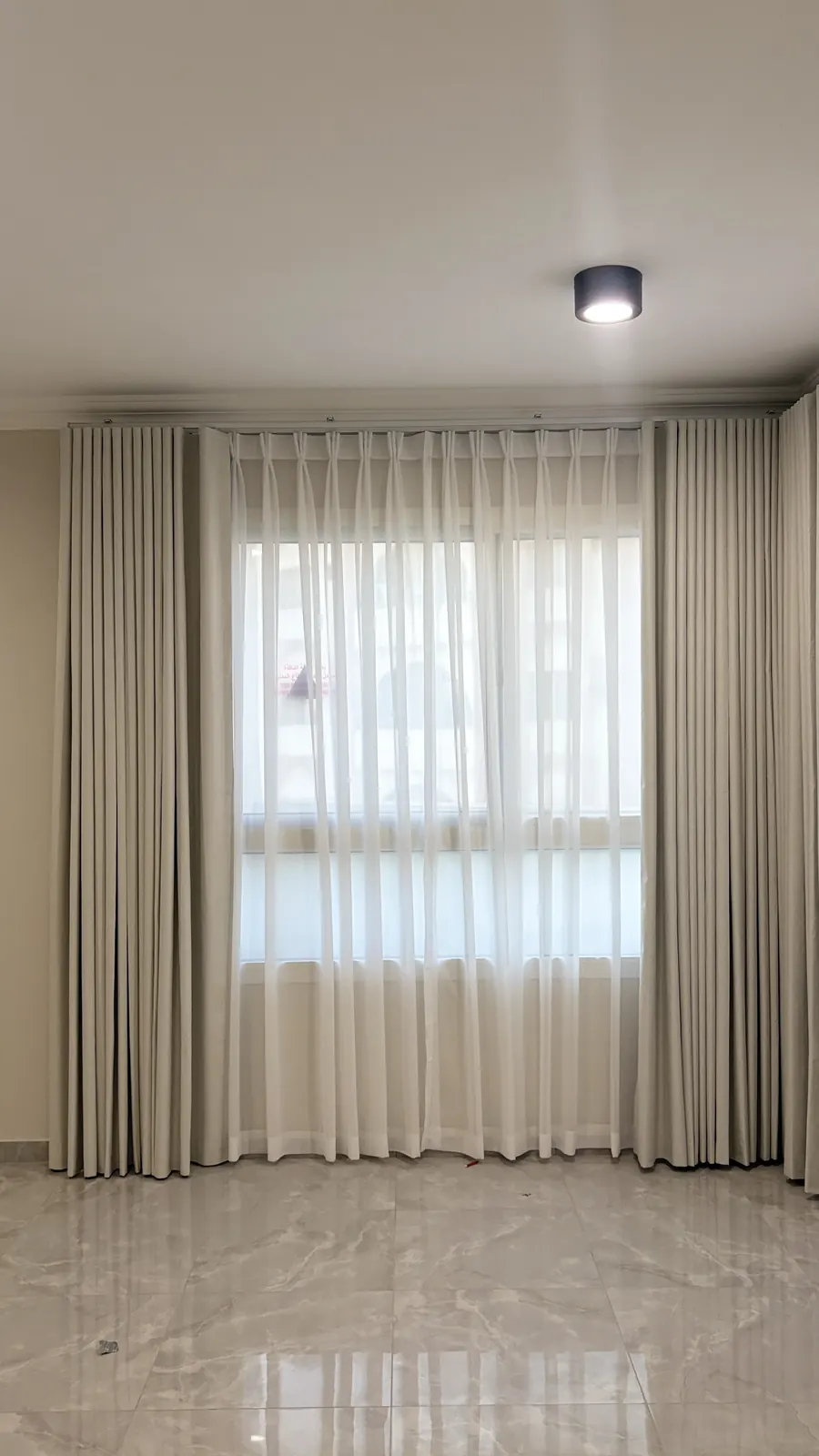Curtains and a sheer on a ceiling track above a marble floor in Doha