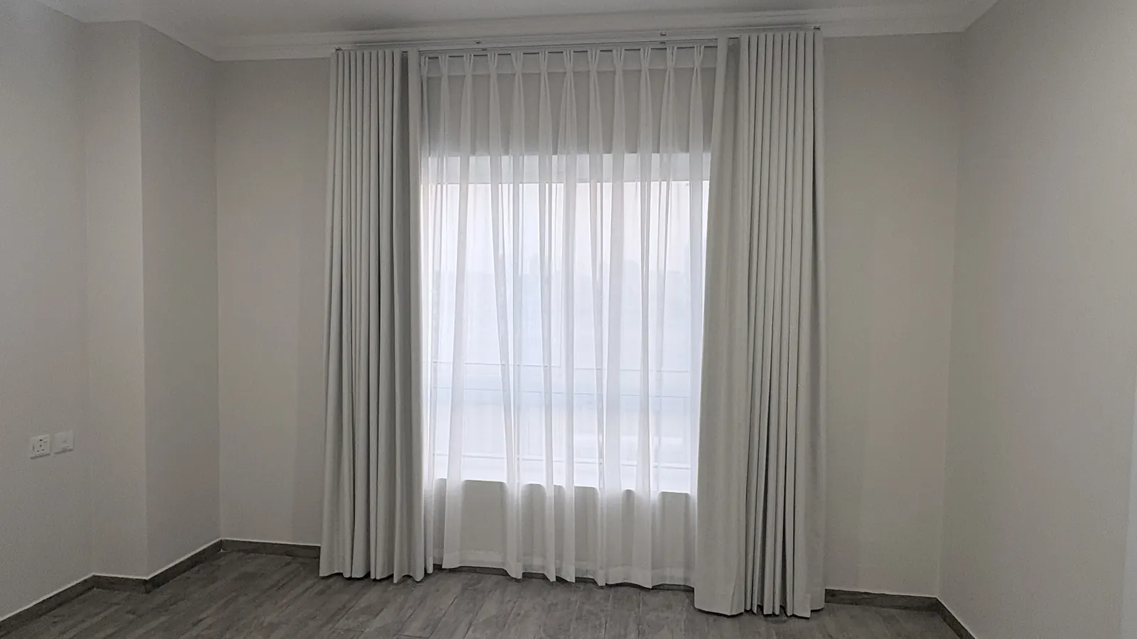 Grey curtains and a sheer on a bedroom window in Doha