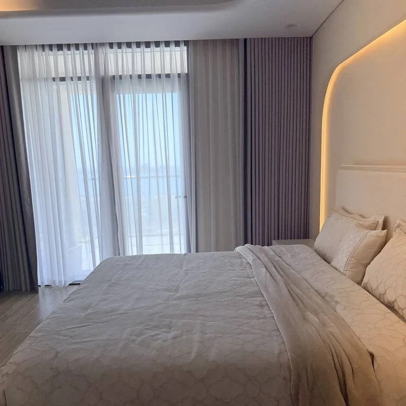 Bedroom with grey wave curtains and white sheers on a ceiling track in Doha