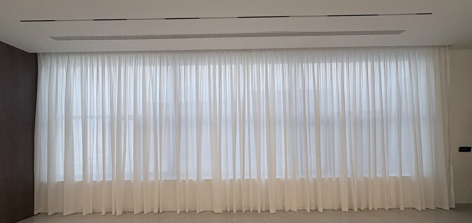 White sheer curtain wall beside wood panels in a Doha villa